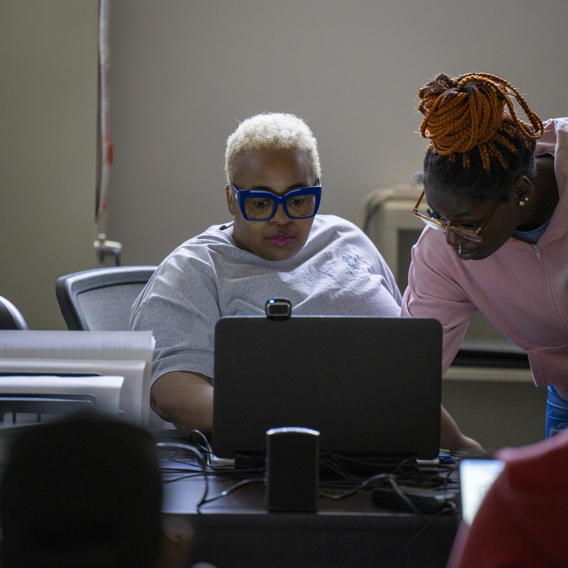Two Support Solutions orientation participants working together at a laptop.